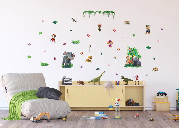 Wandsticker Set mit Paw Patrol Jungle Pups Motiven in einem hellen Kinderzimmer über einem gelben Regal und einem beigen Sessel.