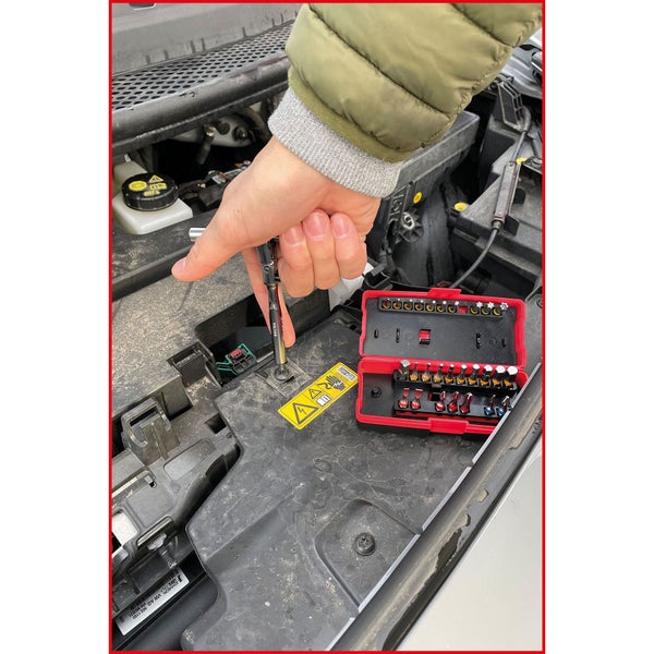 Hand schraubt mit Schraubendreher und Bit-Set im Motorraum