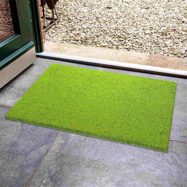 Grüne Fußmatte vor einer Haustür.
