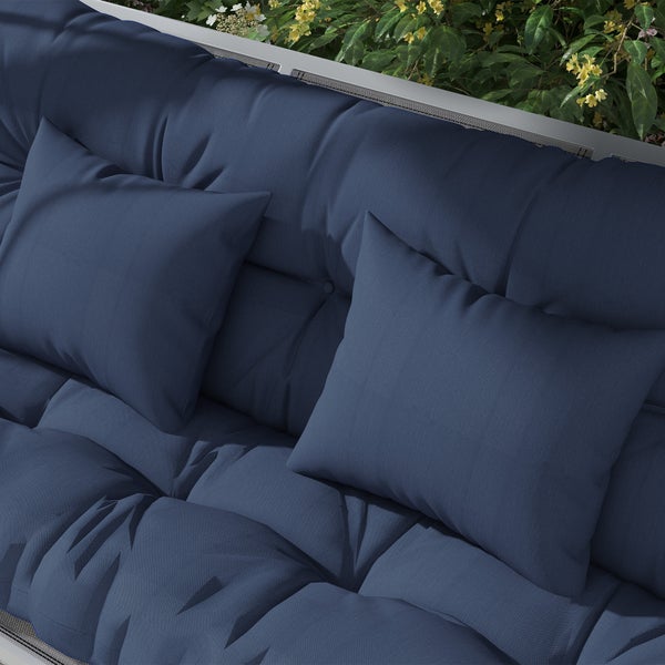 Gepolstertes Lounge Sofa für den Außenbereich mit zwei Zierkissen und Metallrahmen vor einer Gartenpflanze