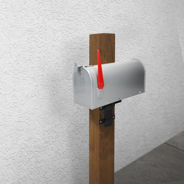 Amerikanischer Briefkasten aus silbernem Metall mit roter Fahne, montiert auf einem braunen Holzpfosten.