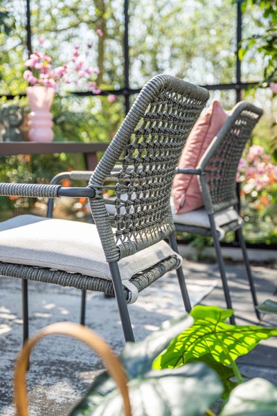 Gartenstühle mit Seilgeflecht und Sitzkissen auf einer hellen Terrasse.