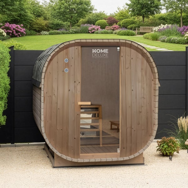 Fasssauna aus Holz von Home Deluxe mit Glastür im Garten aufgestellt