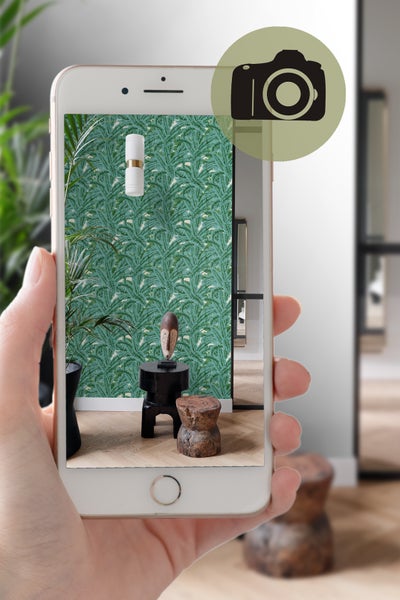 Einrichtungsbeispiel mit Palmenblatt-Tapete, Tisch, Hocker und Dekoration, aufgenommen mit einem Smartphone.