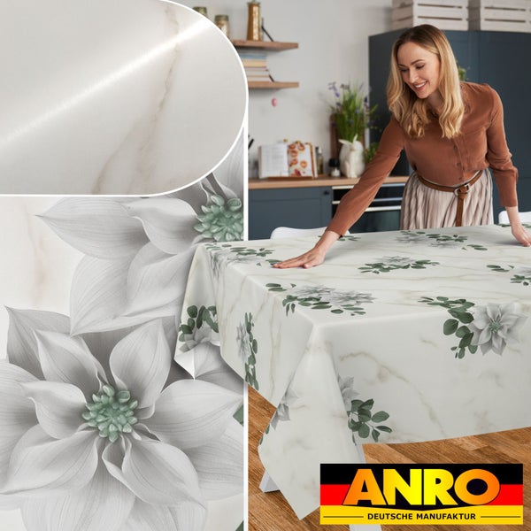 Abwaschbare Tischdecke in Marmor-Optik mit Blumenmuster auf einem Küchentisch. Eine Frau streicht das Tischtuch glatt. Anro Deutsche Manufaktur Logo.