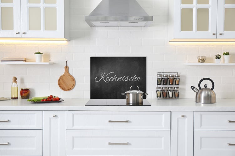 Helle Küche mit weißen Schränken, Kochfeld, Dunstabzugshaube und Küchenutensilien.