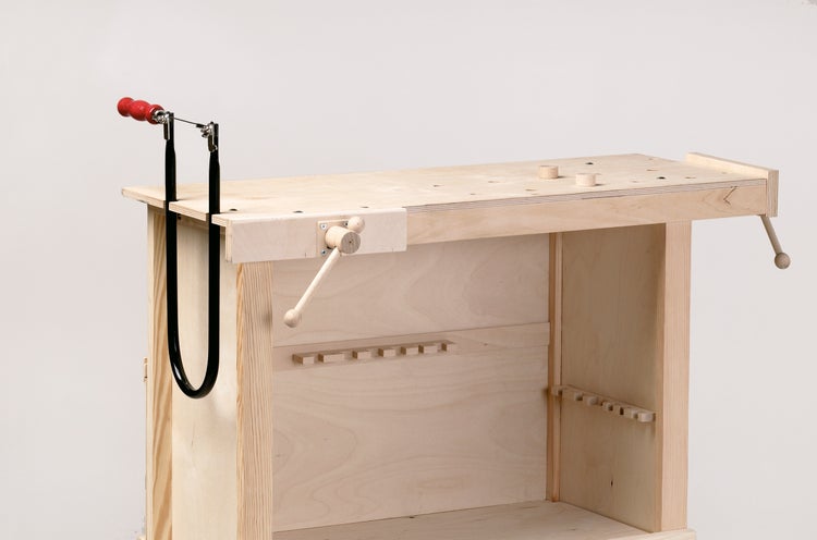 Eine Werkbank aus hellem Holz mit integriertem Schraubstock und einer Laubsäge, ideal für Kinder zum handwerklichen Arbeiten.
