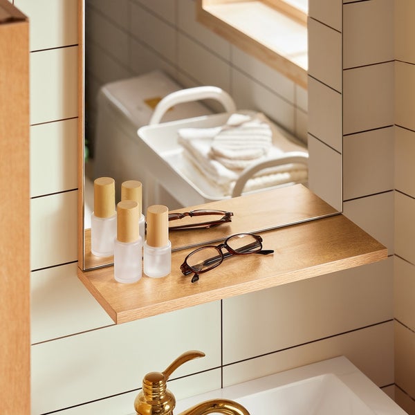 Spiegel mit Ablage im Badezimmer mit Flaschen und Brille