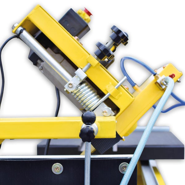 Detailaufnahme einer Fliesenschneidmaschine mit gelbem Rahmen und schwarzem Maschinentisch.