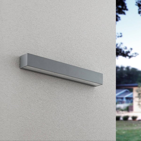 Moderne rechteckige Außenwandleuchte aus grauem Metall an einer strukturierten Fassade.