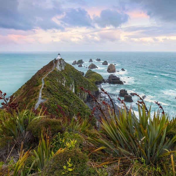 Landschaft mit Leuchtturm auf einer Landzunge mit Meer im Hintergrund