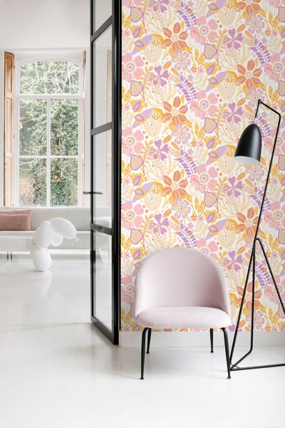 Helles Wohnzimmer mit einer Tapete mit floralem Muster, einem hellrosafarbenen Samtsessel und einer schwarzen Stehlampe.