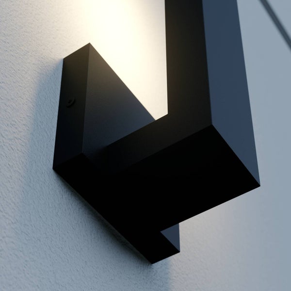 Moderne schwarze LED-Wandleuchte mit eckigem Design an einer strukturierten Wand mit warmweißem Licht.