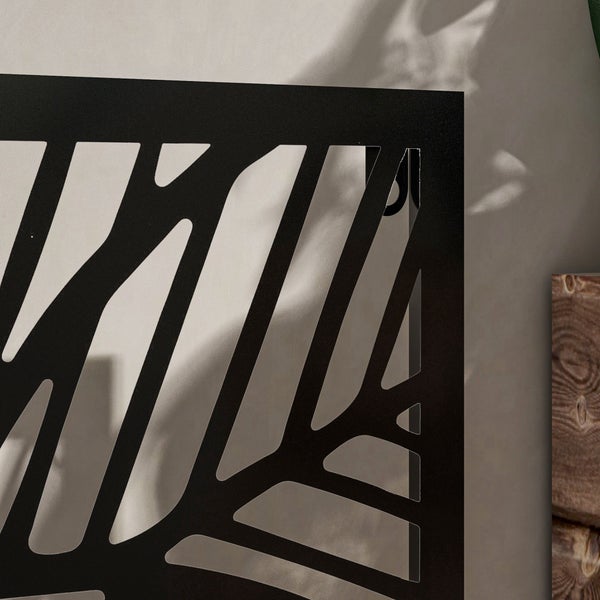 Detailansicht eines schwarzen Sichtschutzelements aus Metall mit einem abstrakten geometrischen Linienmuster.