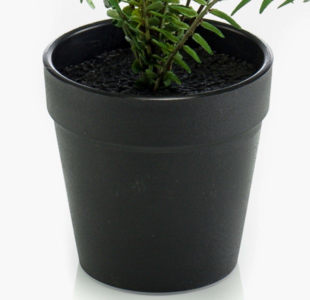 Schwarzer Kunststoff-Blumentopf mit grüner Kunstpflanze in dunkler Erde-Optik.