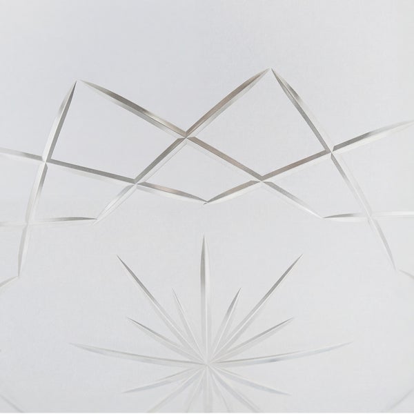 Detailansicht von eingravierten geometrischen Linien und einem Sternmuster auf einer Glasoberfläche.