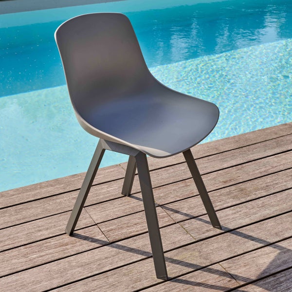 Moderner grauer Gartenstuhl mit Kunststoff-Sitzschale auf einer Holzterrasse neben einem Swimmingpool.