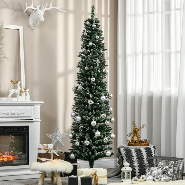 Schmaler künstlicher Tannenbaum, grün, mit silbernen Kugeln, in einem weihnachtlich dekorierten Zimmer neben einem Kamin und Geschenken.