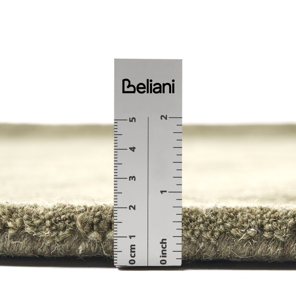 Nahaufnahme eines Teppichs mit einem Lineal zur Messung der Florhöhe in Zentimetern und Zoll, Beliani Logo.