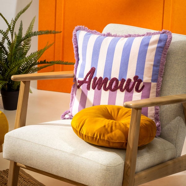 Dekoratives Kissen mit dem Wort Amour auf einem Sessel