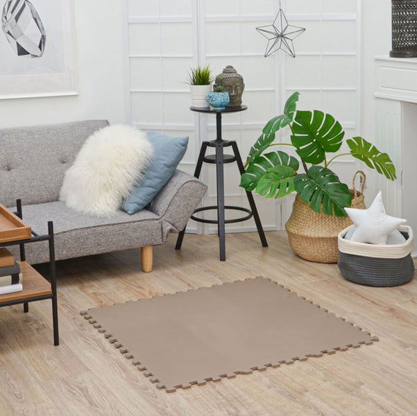 Quadratische braune Bodenschutzmatte aus Schaumstoff mit Puzzlerand auf hellem Holzboden in einem modern eingerichteten Wohnzimmer.
