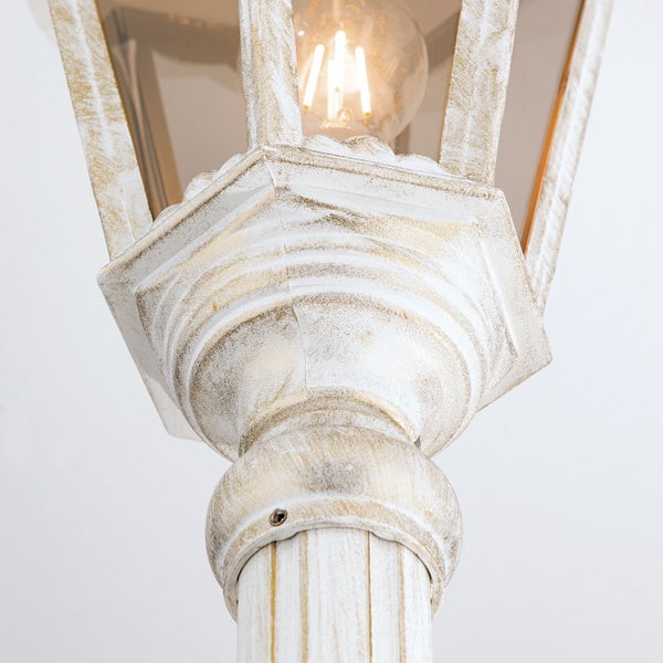 Detailansicht einer Außenlaterne im Vintage-Stil mit patinierter Oberfläche und leuchtendem Leuchtmittel.