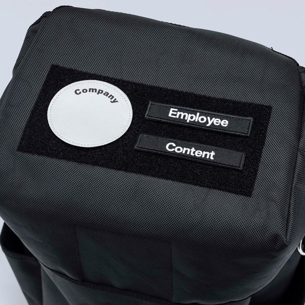 Detailansicht einer schwarzen Tasche mit Klettflächen für Beschriftungen wie Firma, Mitarbeiter und Inhalt