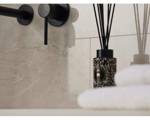 Wandfliesen in Marmoroptik im Badezimmer mit schwarzer Armatur, Raumduft und weißen Handtüchern.