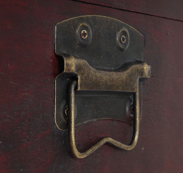 Detailansicht eines Truhengriffs aus Metall mit Schrauben an einer Holztruhe