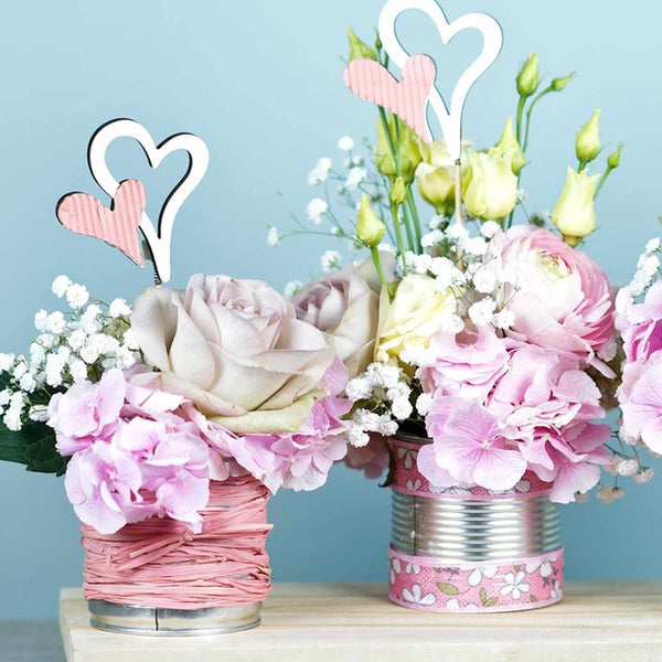 Zwei Blumengestecke mit Herzen in dekorierten Dosen