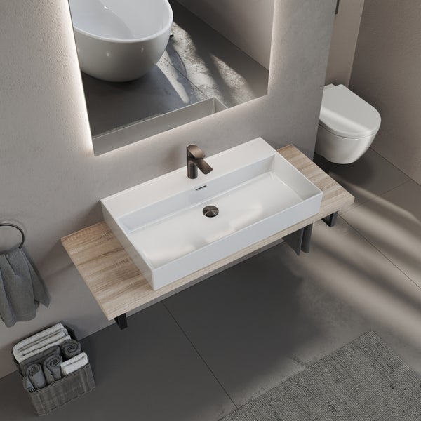 Modernes Badezimmer mit rechteckigem weißem Aufsatzwaschbecken aus Keramik auf einer Holzkonsole, dunkler Armatur und beleuchtetem Spiegel.