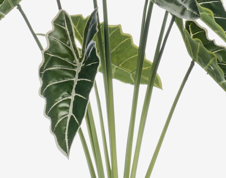 Künstliche Pflanze in einem schwarzen Blumentopf mit grünen Stielen.