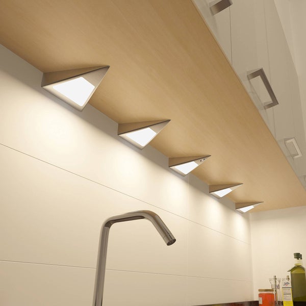 Dreieckige LED-Unterbauleuchten in Edelstahl-Optik unter einem Küchenschrank montiert, die eine Fliesenwand hell beleuchten.