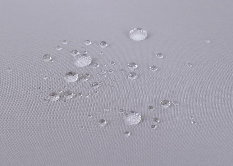 Wassertropfen perlen auf einer wasserabweisenden Stoffoberfläche ab.
