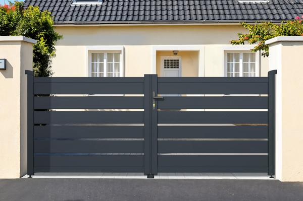 Graues Schiebetor aus Aluminium vor einem Wohnhaus