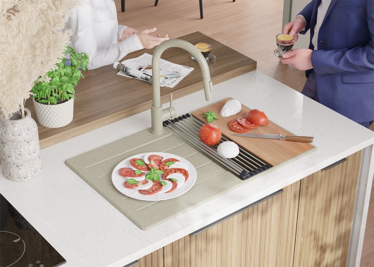 Küchenspüle mit Armatur, Abtropfgitter und Zutaten für Caprese-Salat auf einer Küchentheke.