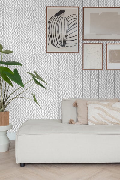 Wohnzimmer mit Couch, Zimmerpflanze und Tapete mit Pfeilmuster