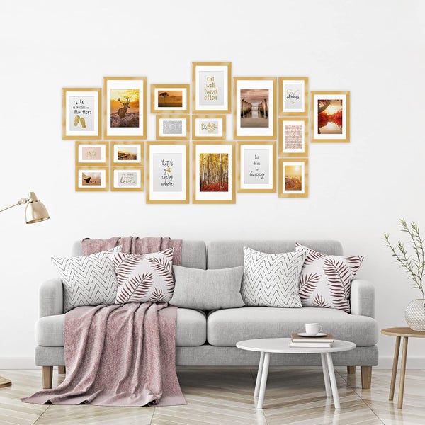 Wohnzimmer mit grauer Couch und einer Bildergalerie aus mehreren unterschiedlich großen Bilderrahmen mit verschiedenen Motiven an der Wand.