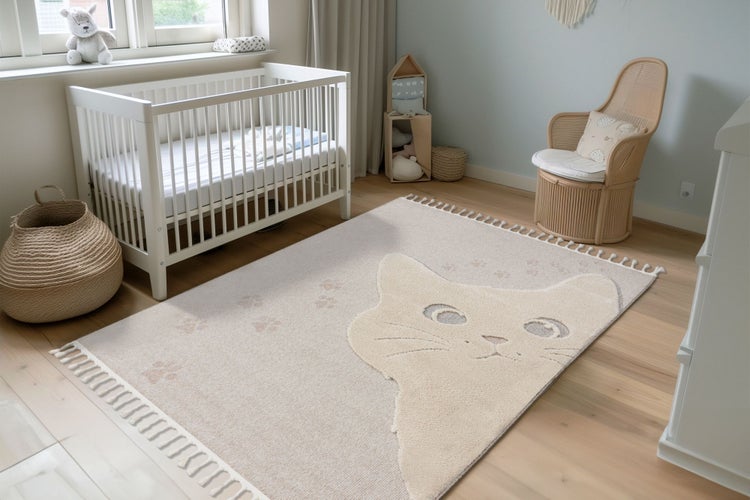 Ein Kinderzimmer mit einem rechteckigen Kinderteppich mit Katzenmotiv, einem weißen Gitterbett, einem Rattansessel und hellen Holzböden.