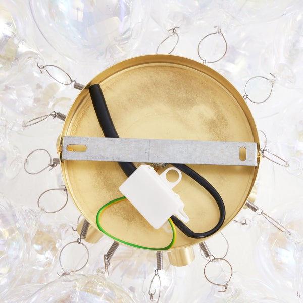 Detailaufnahme einer Deckenleuchte mit goldenem Baldachin und elektrischen Anschlüssen.