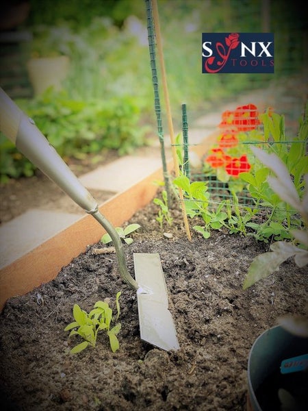 Gartenhacke im Einsatz in einem Hochbeet mit jungen Pflanzen und SYNX Tools Logo