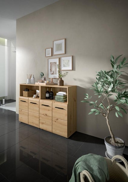 Breiter Badschrank in Eichenoptik mit vier Türen, schwarzen Griffen und zwei offenen Regalfächern, dekoriert in einem modernen Badezimmer.