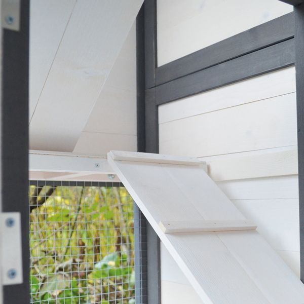 Innenansicht eines Kleintierstalls mit einer Holzrampe und Drahtgitter.