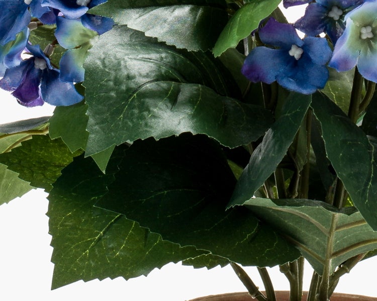 Künstliche Pflanze mit gezackten grünen Blättern und blauen Blüten aus Textil.