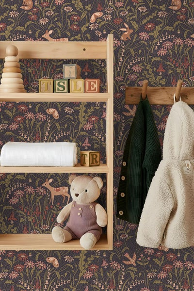 Vliestapete mit Waldtiermotiv und Blumen im Kinderzimmer über einer Wandvertäfelung und einem Kinderbett aus Holz.