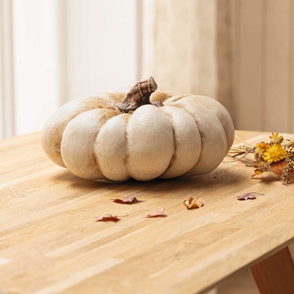 Dekorativer Kürbis auf Holztisch mit Herbstlaub und Blumen