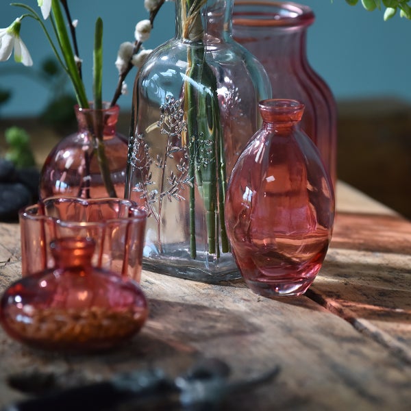 Dekorative Glasvasen in verschiedenen Formen und Größen auf einem Holztisch arrangiert.