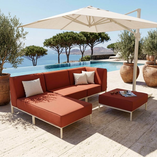 Moderne Lounge-Garnitur auf einer Terrasse am Pool, bestehend aus einem rostroten Ecksofa, Hocker und großem Sonnenschirm.