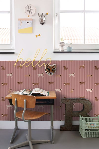 Ein Kinderzimmer mit einem Schreibtisch, einem Stuhl und einer Wand mit einem Hundemuster.