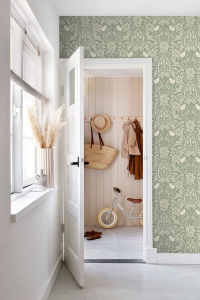 Vliestapete mit floralem Muster und Vögeln in einem hellen Flur mit einer weißen Tür und Blick auf eine Holzvertäfelung.